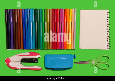 colored felt pens, scissors, notebook and a stapler lying on a green background. concept of office and educational chancery Stock Photo