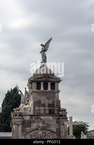 Crypt with angel sculpture on the roof against the cloudy sky in Poblenou Cemetery. Stock Photo