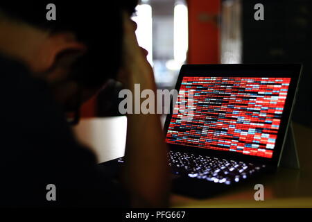 Computer Hacker silhouette typing on computer in a dark room. Working on binary code technology. binary data, computer crime and network security Stock Photo