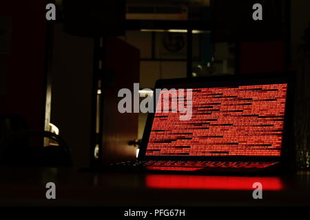 Computer crime. computer with red code in a dark room. Working on binary code technology. binary data, computer crime and network security concepts. Stock Photo