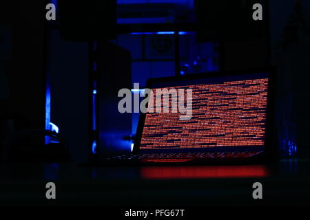 Computer crime. computer with red code in a dark room. Working on binary code technology. binary data, computer crime and network security concepts. Stock Photo