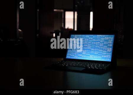 Computer Hacker silhouette typing on computer in a dark room. Working on blue binary code technology. binary data, computer programming and network Stock Photo