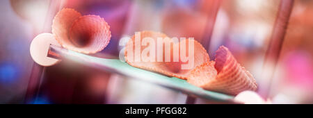 Empty sweet ice cream cones on display in gelateria. Icecream cones dreamy pink bokeh web banner. Gelato Summer Refreshment. Stock Photo