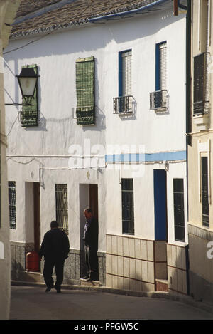 Spain, Andalusia, whitewashed houses on the main street of Cabra, with two old men. Stock Photo