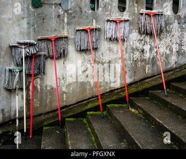 Several mops against a dirty old wall : spring cleaning concept Stock Photo