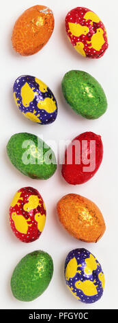 Ten chocolate eggs covered in coloured and patterned foil. Stock Photo