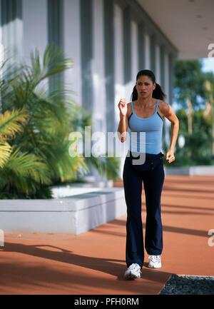 Woman in tank top and tracksuit bottoms power walking Stock Photo