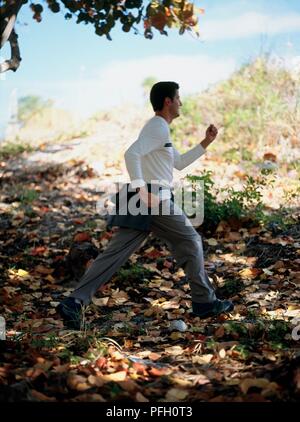Man jogging through woodland area, side view Stock Photo
