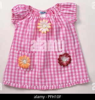 Pink and white gingham baby dress with fabric flowers on pockets and chest, elastic cuffs and neck. Stock Photo