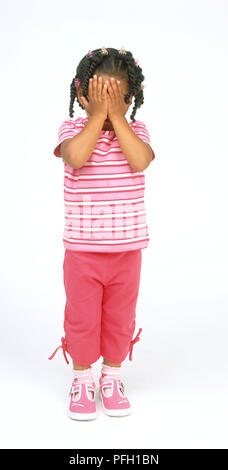 Girl standing with hands over her face Stock Photo