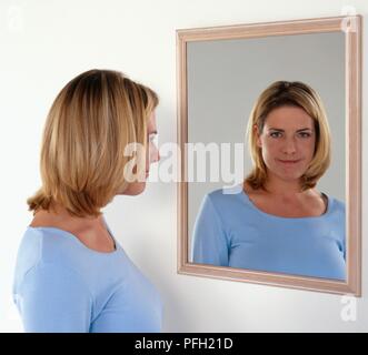 Woman looking at her reflection in the mirror Stock Photo