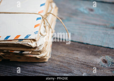 stack of old letters in envelopes, tied with thread, on a wooden table Stock Photo