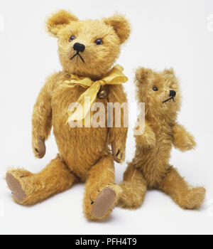 Two teddy bears sitting side by side, larger one wearing bow tie,side view Stock Photo