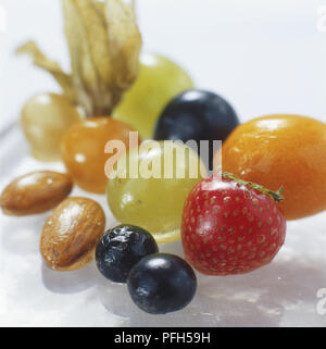 Selection of sugar-dipped fruit and nuts, including grapes, kumquats, physalis, almonds, strawberries and blueberries, close up Stock Photo