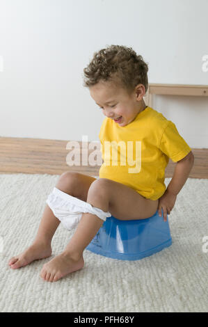 Boy sitting on potty, smiling Stock Photo
