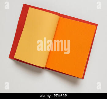 Red blank notebook, open to yellow and orange pages, close-up Stock Photo