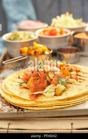 Grilled prawn, avocado, tomato and pineapple on stack of tortillas, and fillings in bowls Stock Photo