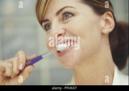 Headshot of woman brushing her teeth, close-up Stock Photo