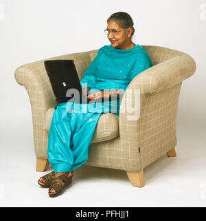 Elderly woman sitting in an armchair and smiling isolated on white ...