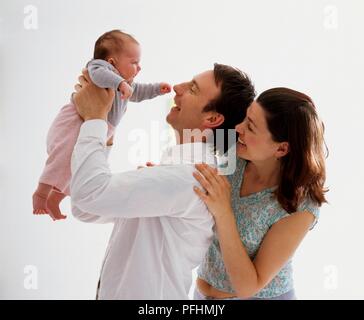 Man and woman with baby girl being held in the air by the man Stock Photo