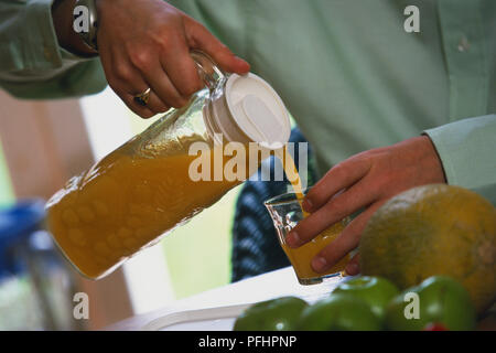 Man pouring orange juice into a glass tumbler Stock Photo