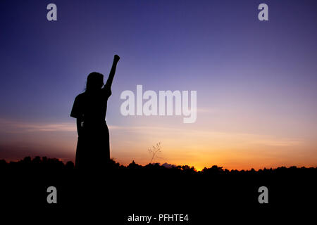 Happy celebrating winning success woman silhouette on sky background. Stock Photo