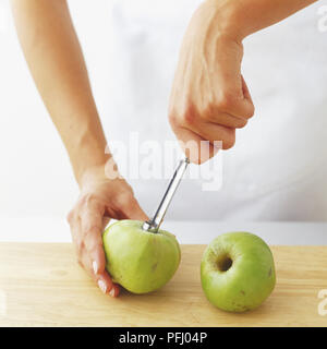 Using a coring tool to removed core from an apple Stock Photo