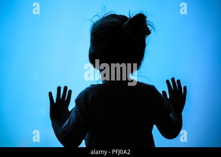 Silhouette of little girl looking into fish tank Stock Photo