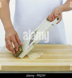 Potato being thinly sliced using mandolin, front view Stock Photo