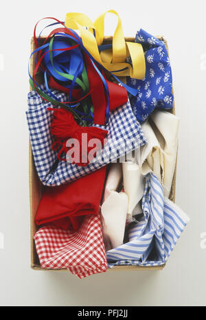A selection of different coloured fabrics, ribbons and wool in a cardboard box, view from above Stock Photo