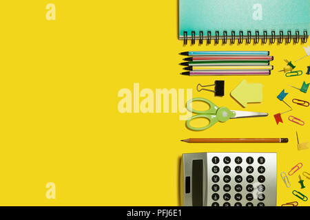 multiple school and office suplies and gadgets lying diagonally on a yellow background. free space for text Stock Photo