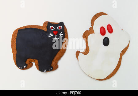 Biscuits iced and shaped as a ghost and a black cat, close up. Stock Photo