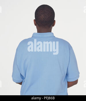 Dark skinned young man with close-cropped black hair, wearing blue polo shirt, view from behind Stock Photo
