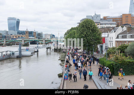 Tourists walking alongside the River Thames at Bankside viewed from Millennium Bridge in London