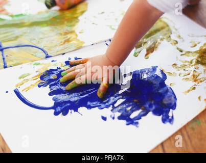 Child's hand on surface covered in blue paint Stock Photo