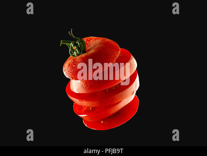 5 Flying tomato slices on a black background Stock Photo