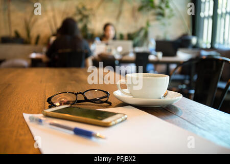Selected focus coffee cup and glasses with pen and paper on wooden background Stock Photo