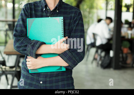 Young student holding notebook with group mates in blur background Stock Photo