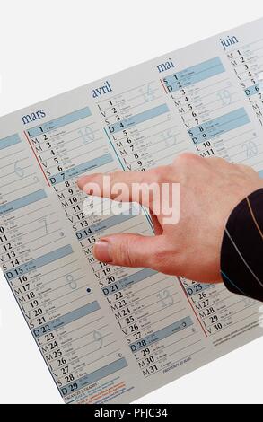 Man's hand pointing on calendar with French text on it Stock Photo