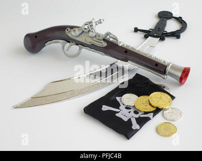 Pirate's accessories, including toy pistol, toy sabre sword, purse with skull on, and silver and gold coins Stock Photo