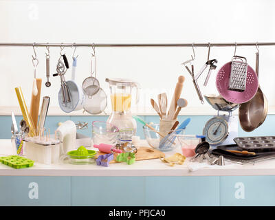 Various cooking and baking utensils on shelf and hanging from rail Stock Photo