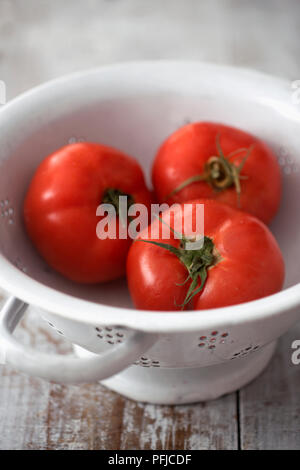 Three beefsteak tomatoes in colander, close-up Stock Photo