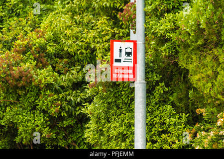 Railway sign 'Keep back from the platform edge' on the background of the lush foliage Stock Photo
