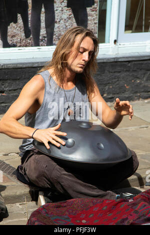 Street Busker sat on a street in York playing a Hang Drum, North Yorkshire, England, UK. Stock Photo