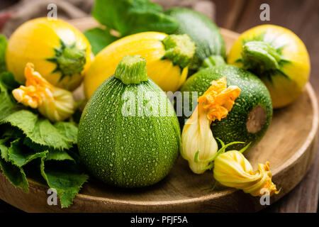 Zucchini with leaves and flowers on dark wooden rustic background Stock Photo