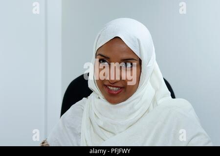 Young woman in white headscarf, smiling, close-up Stock Photo