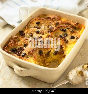 Bread and butter pudding in baking tray, spoon nearby Stock Photo