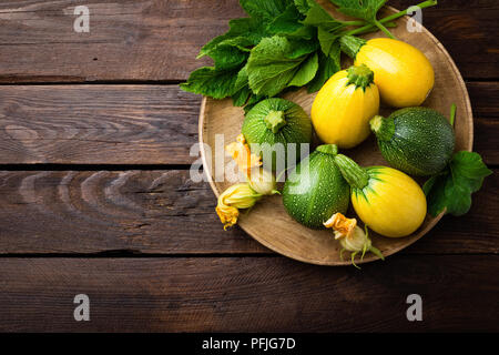Zucchini with leaves and flowers on dark wooden rustic background Stock Photo