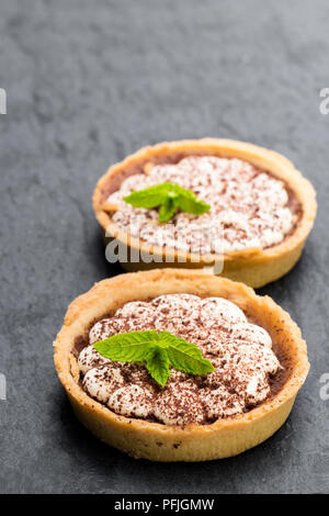 Mini  banoffee pie tarts isolated on black stone background Stock Photo