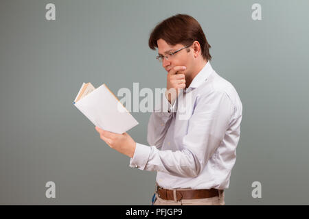 Focused on a reading book student is in the park near the university. Pleasant guy preparing for the serious exam after the break. Close up Stock Photo